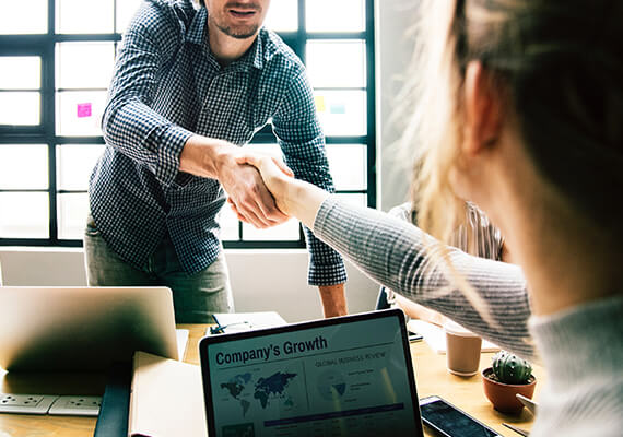 man standing and shaking hands with a woman